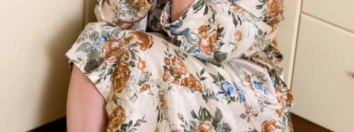 אישה יושבת על הרצפה ומחזיקה את הראש בין הידיים